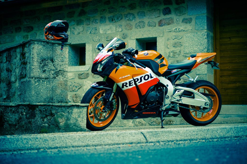 Honda CBR Fireblade Repsol sportbike in orange red white near stone wall with HJC helmet Wallpaper