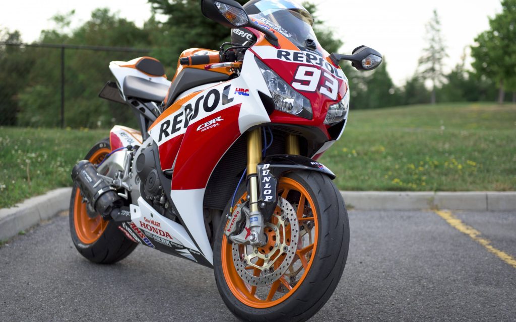 Honda CBR1000RR Repsol #93 sport bike with vibrant orange red racing colors and gold forks outdoors Wallpaper