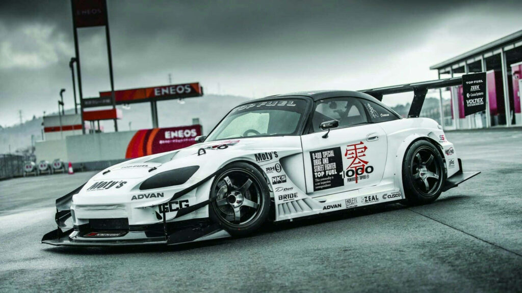 Customized Honda S2000 race car with wide-body kit and bold decals on overcast racetrack background Wallpaper