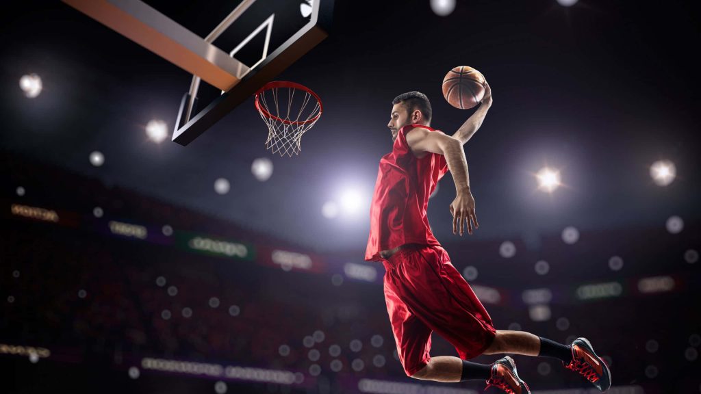 Basketball player in red jersey mid-air slam dunk bright arena intense sports action wallpaper
