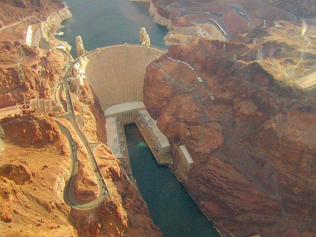 Aerial view of Hoover Dam at golden hour spanning Colorado River canyon in desert landscape Wallpaper