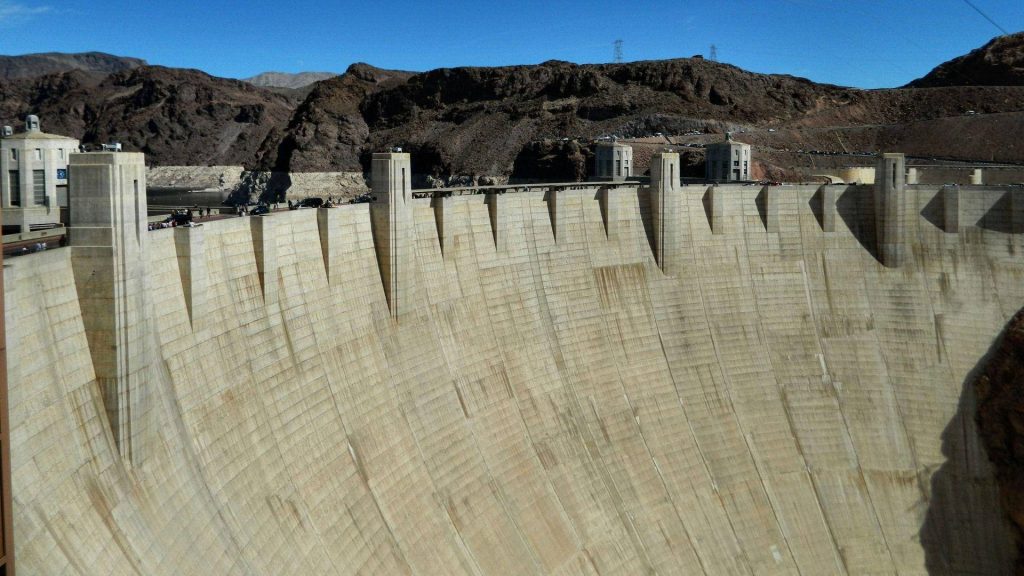 High-angle view of Hoover Dam concrete structure against rugged canyon under clear blue sky Wallpaper