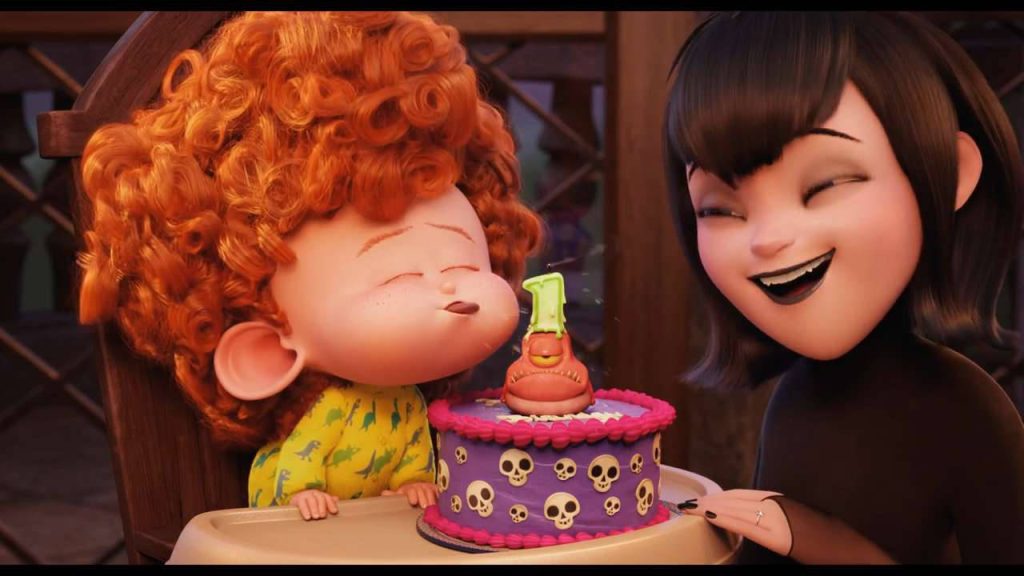 Dennis with curly red hair blowing birthday candle on purple skull cake with smiling Mavis Wallpaper