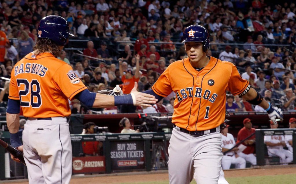 Houston Astros Colby Rasmus and Carlos Correa high-five in vibrant orange jerseys during night game Wallpaper