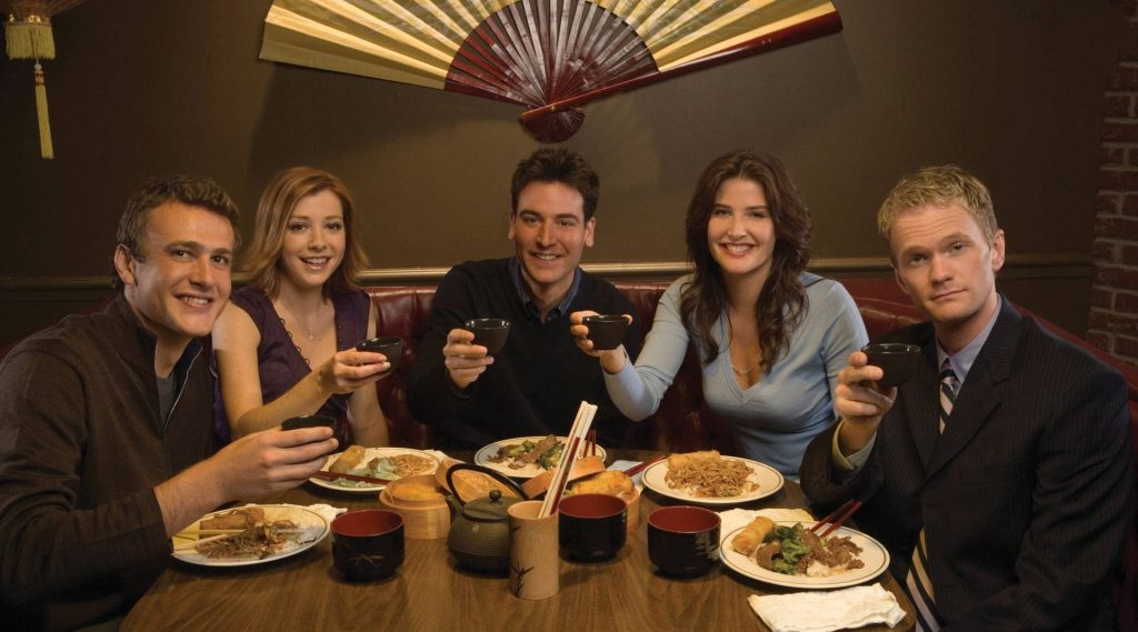 How I Met Your Mother cast enjoying a cheerful toast in restaurant wallpaper background
