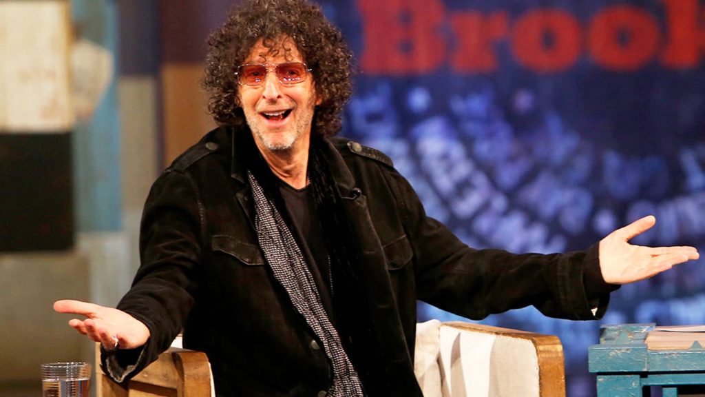 High-resolution image of Howard Stern in studio with curly hair glasses black jacket Brooklyn sign Wallpaper
