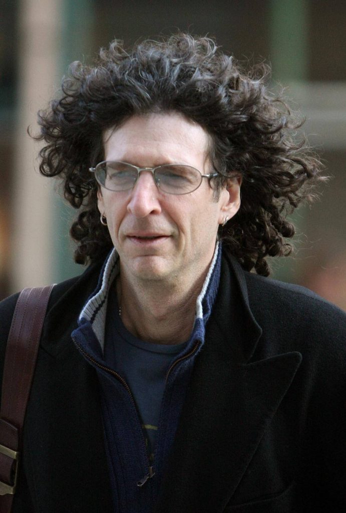 Portrait of radio host Howard Stern with curly hair glasses dark jacket soft blurred background Wallpaper