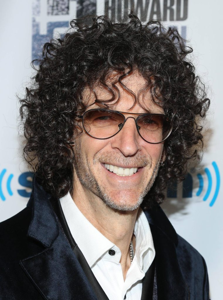 Howard Stern portrait with curly hair glasses white shirt dark blazer SiriusXM backdrop Wallpaper