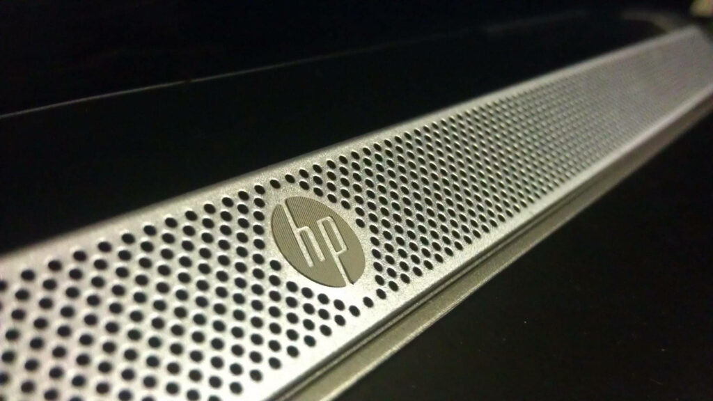 Emphasizing HP Laptop's Sleek Metallic Branding on Speaker Texture Wallpaper