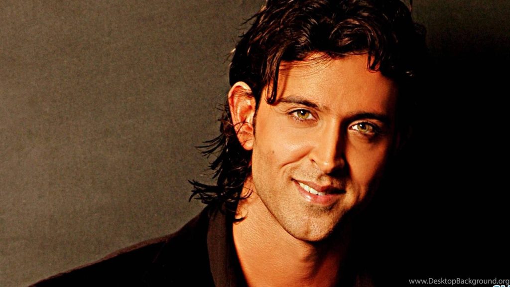 Close-up of Indian superstar Hrithik Roshan with warm smile and hazel eyes in dramatic lighting Wallpaper