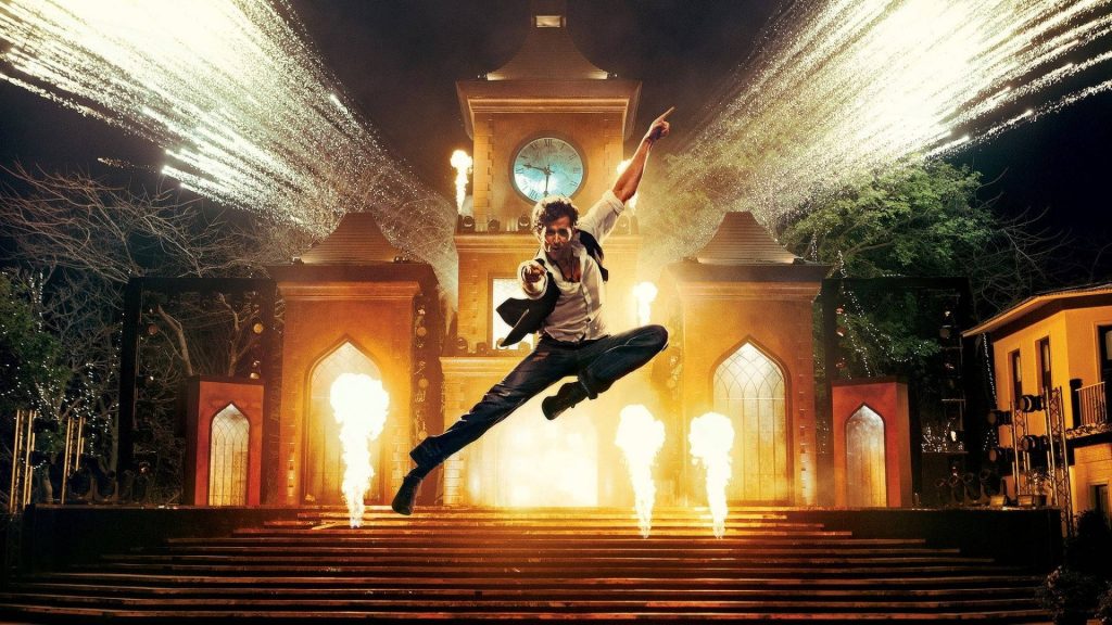 Hrithik Roshan leaps mid-air by clock tower with fireworks and golden flames cinematic wallpaper