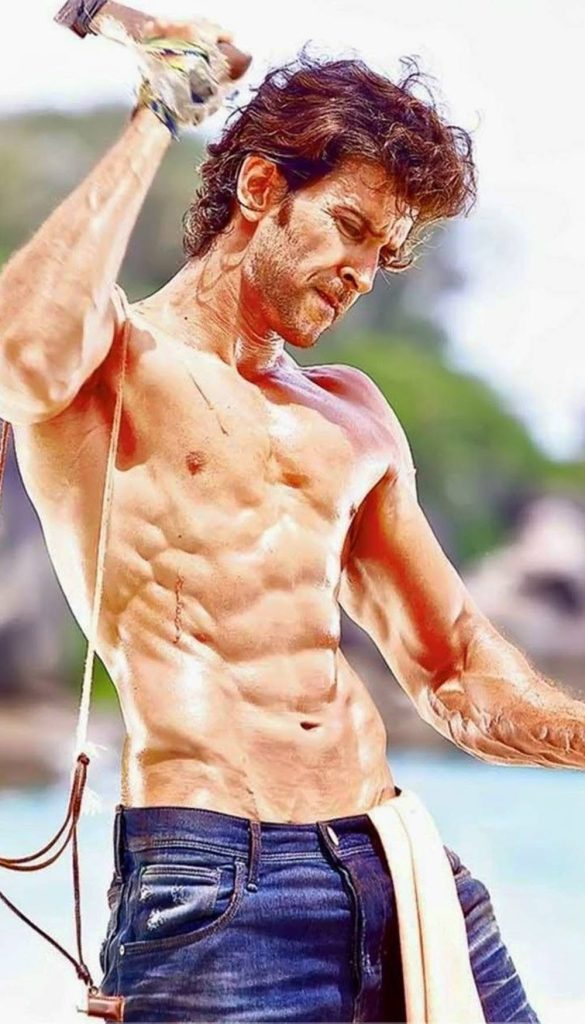 Hrithik Roshan shirtless muscular physique rugged jeans holding tool tropical background wallpaper