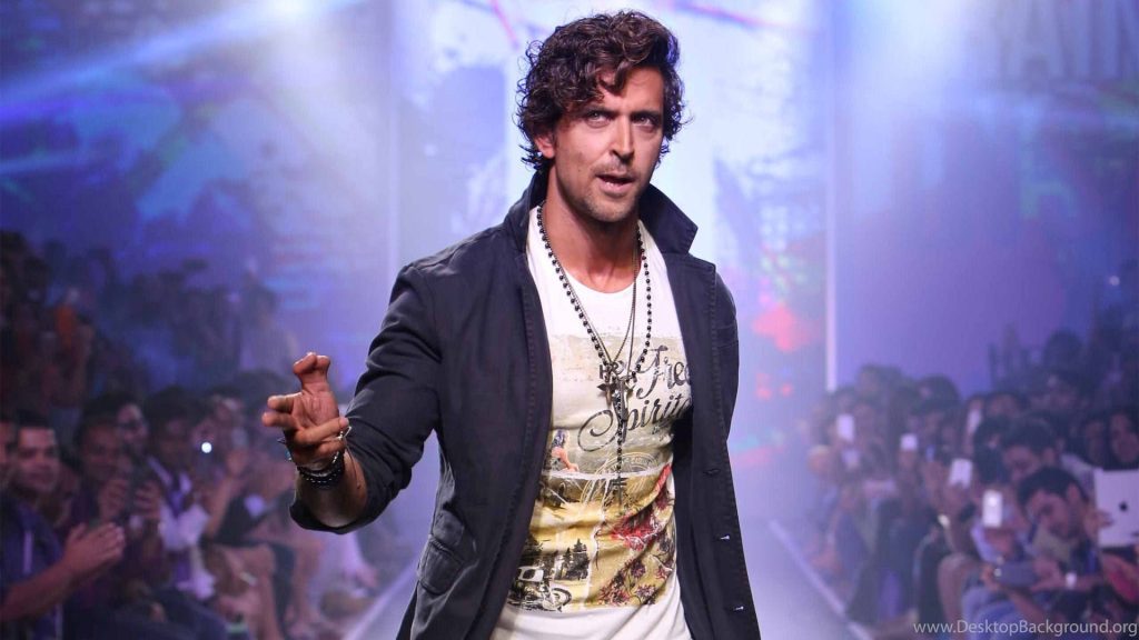 Hrithik Roshan stylish in dark jacket and graphic tee on vibrant Bollywood fashion show runway Wallpaper