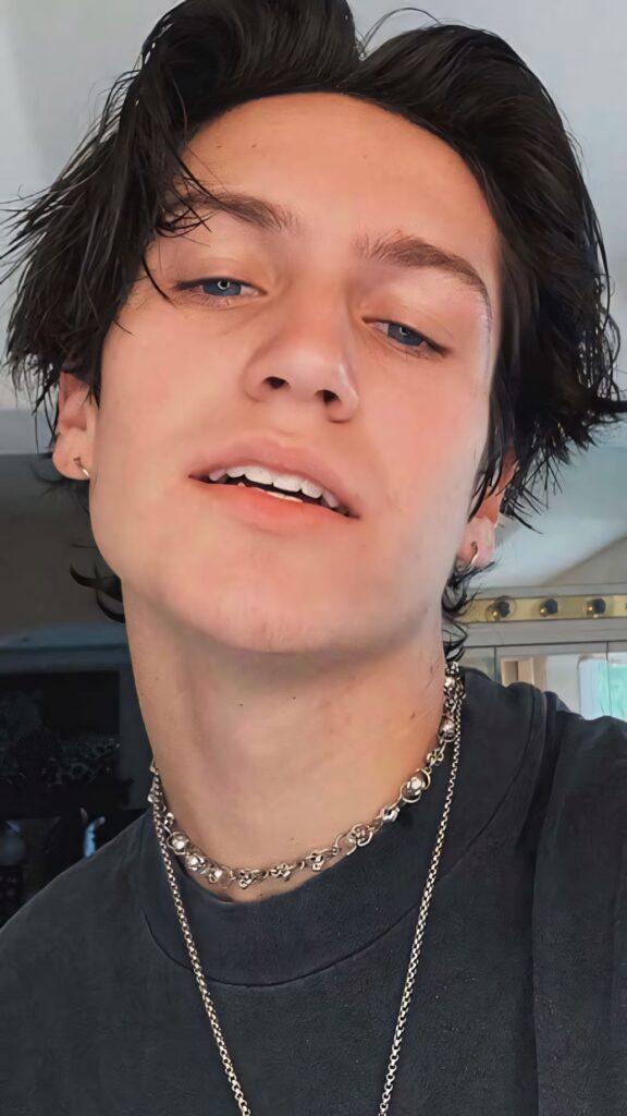 Close-up portrait of Chase Hudson with tousled dark hair and silver chains modern style wallpaper