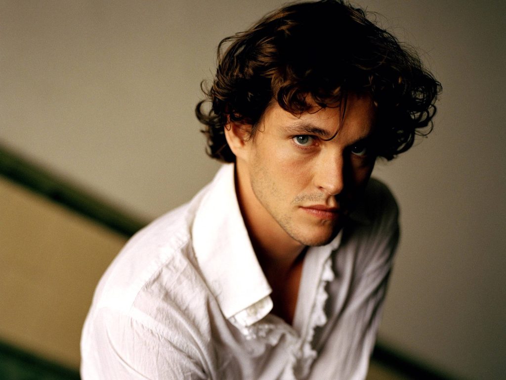 Hugh Dancy portrait intense gaze messy curly hair white ruffled shirt dramatic cinematic lighting Wallpaper