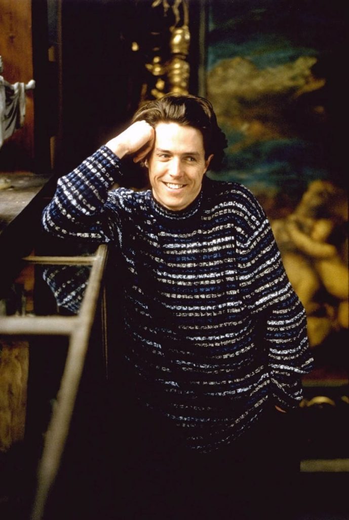 Hugh Grant portrait in patterned Calvin Klein sweater classic 90s style dimly lit background Wallpaper