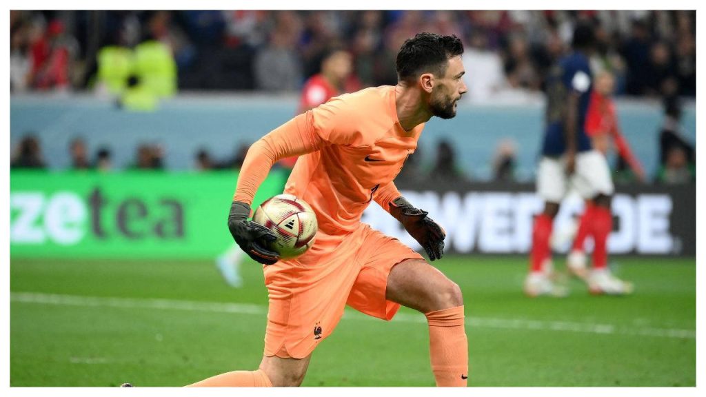 French goalkeeper Hugo Lloris in orange jersey holding ball ready on pitch with blurred stadium background Wallpaper