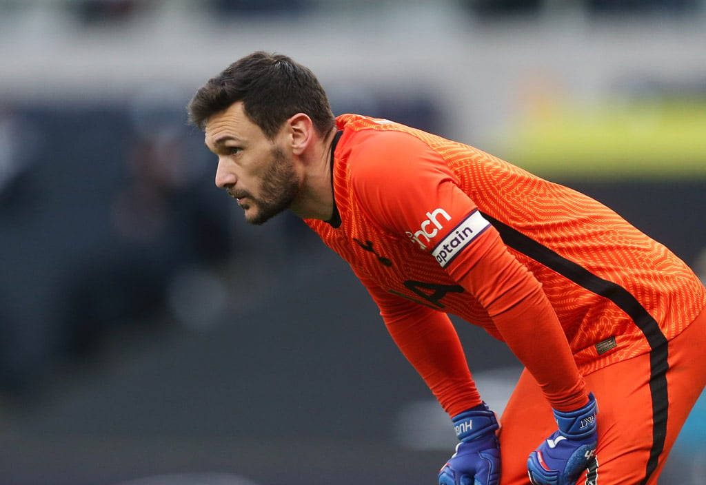 Hugo Lloris goalkeeper in vibrant orange kit with captain armband and blue gloves on pitch Wallpaper