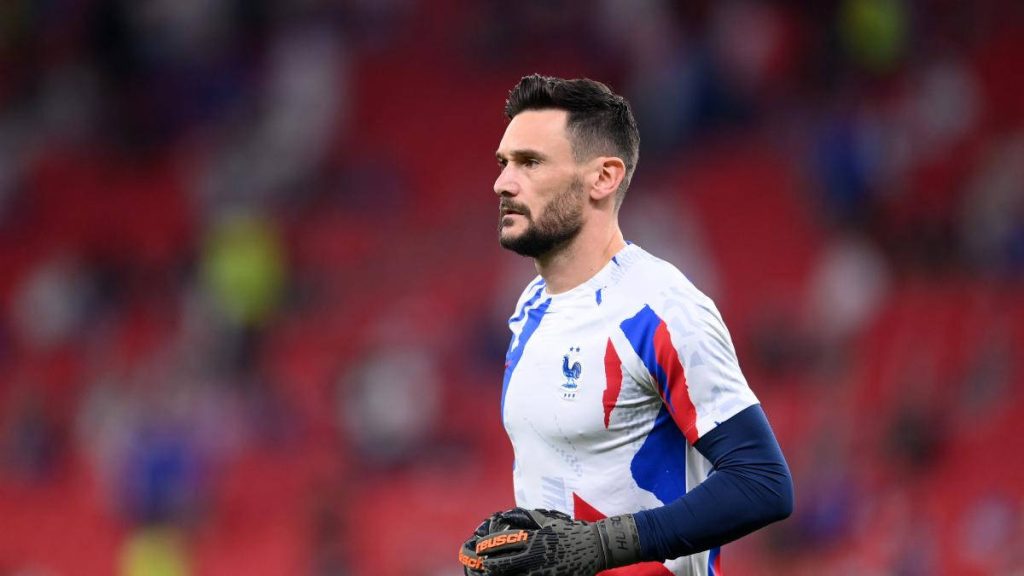 Hugo Lloris focused in French kit and Reusch gloves on vibrant stadium pitch wallpaper background