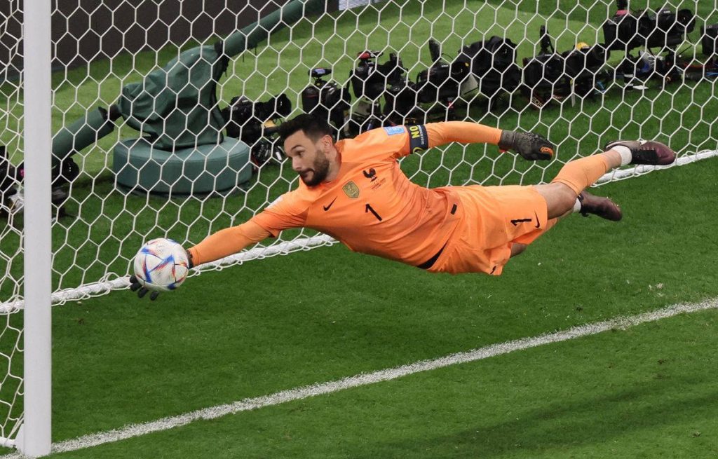 Hugo Lloris diving save in bright orange kit showcasing his skill and focus on soccer field Wallpaper