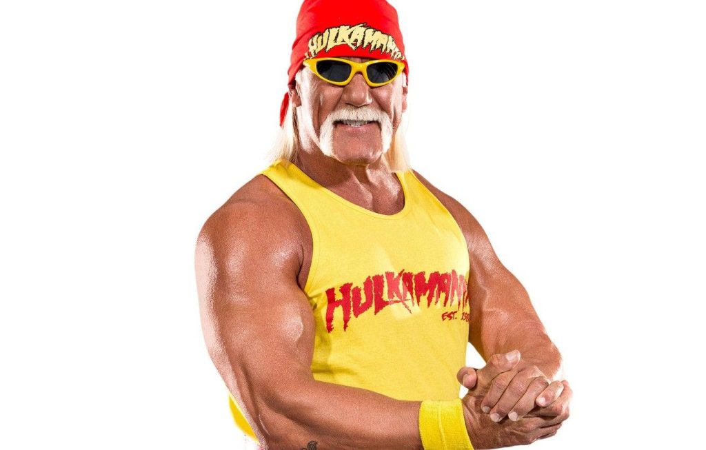 Hulk Hogan flexing muscles in yellow tank top red bandana sunglasses in vibrant studio portrait Wallpaper