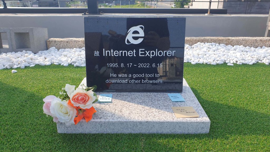 Humorous Internet Explorer tombstone on sunny rooftop with epitaph and flowers background Wallpaper