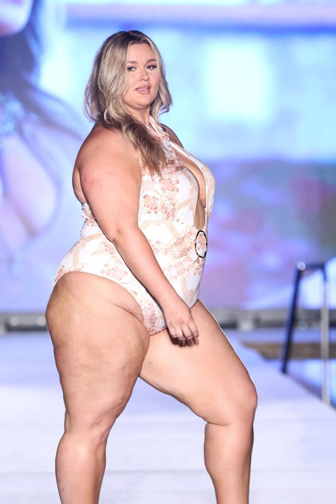 Plus-size model Hunter McGrady in white patterned swimsuit confidently walking runway Wallpaper
