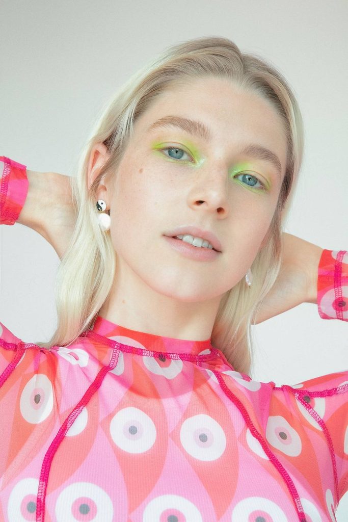 Hunter Schafer vibrant portrait pink red mesh top neon green eyeshadow yin-yang earrings wallpaper