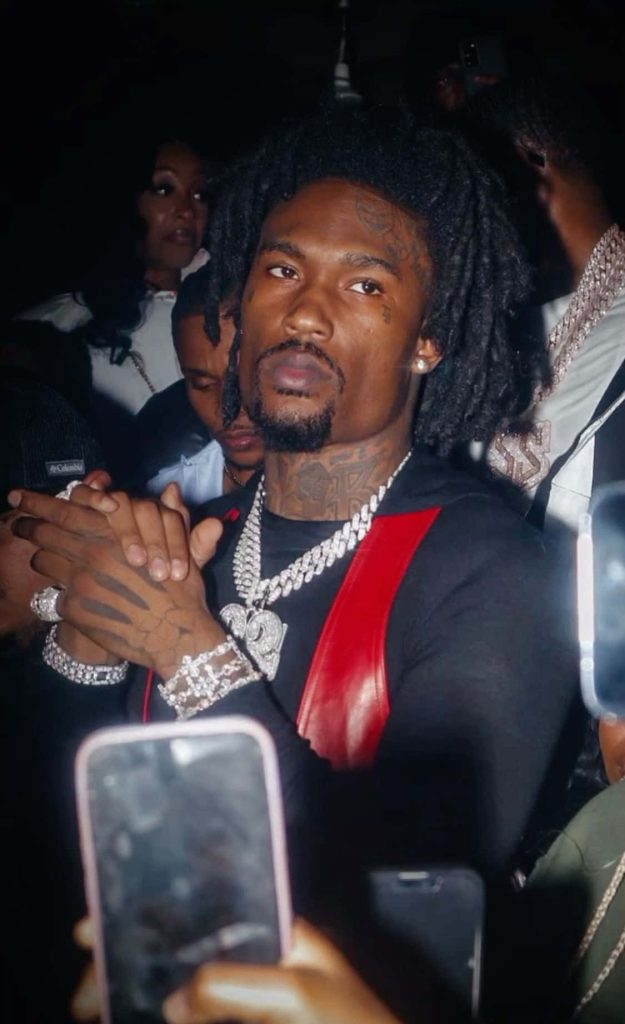 Rapper Hunxho performing live with locs facial tattoos iced-out chains black red outfit Wallpaper