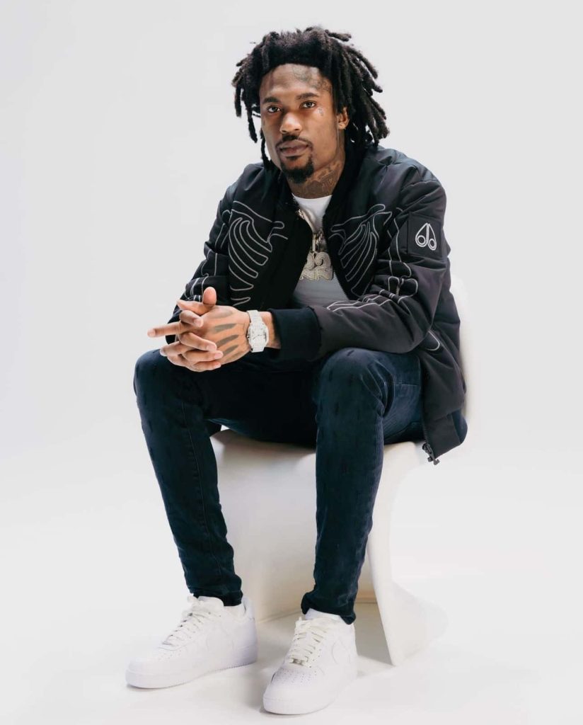 Hunxho rapper studio portrait in black skeleton jacket dark denim and white sneakers background Wallpaper