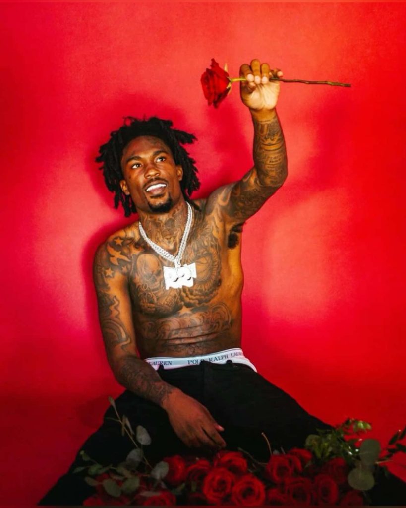 Rapper Hunxho shirtless tattooed holding red rose moody portrait crimson backdrop wallpaper