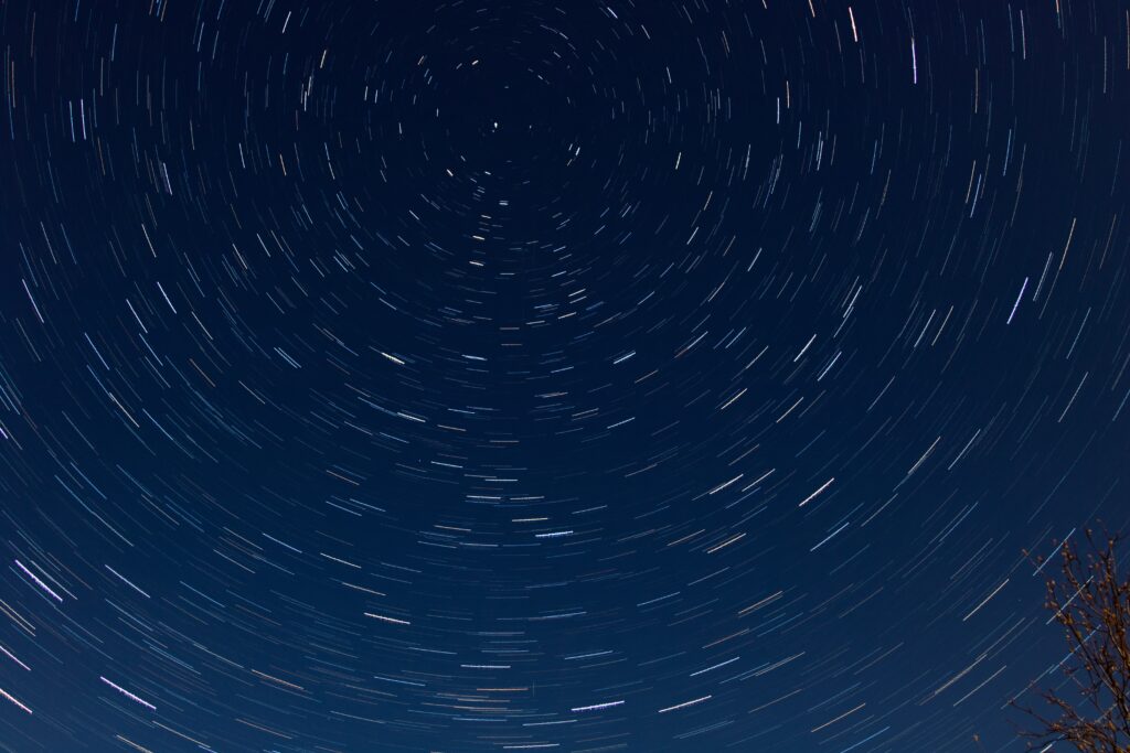 Swirling star trails in deep blue night sky creating a dynamic celestial wallpaper background