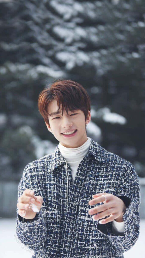 South Korean rapper Hyunjin from Stray Kids smiling with snowy trees winter wallpaper background