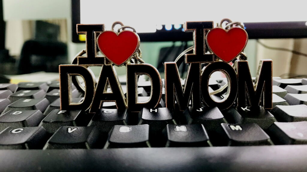 Close-up HD wallpaper of metallic I love Dad and I love Mom ornaments on keyboard background