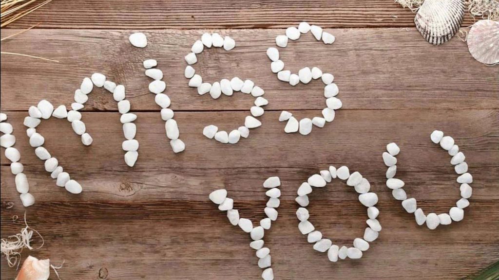 Romantic I miss you message in white pebbles and seashells on rustic wooden beach background Wallpaper