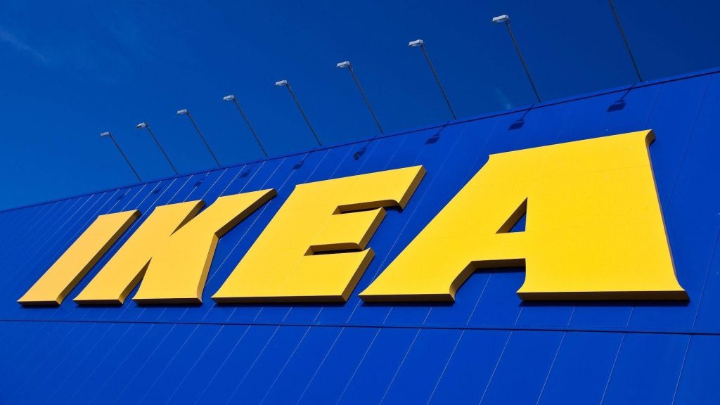 Vibrant IKEA logo with bold yellow letters on deep blue building facade low angle photo wallpaper