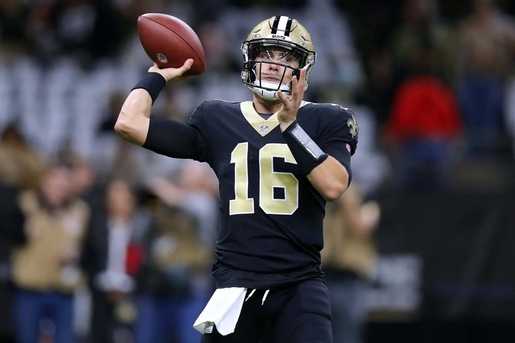 New Orleans Saints quarterback Ian Book in black gold uniform mid-pass NFL action wallpaper