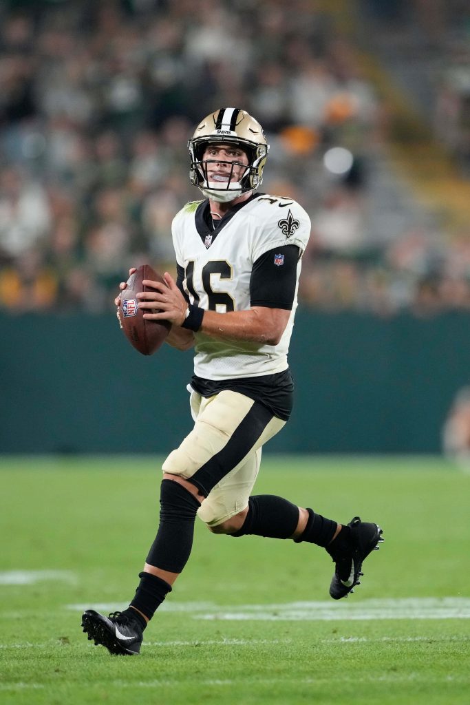 Ian Book New Orleans Saints quarterback scrambling with football in white jersey on turf Wallpaper
