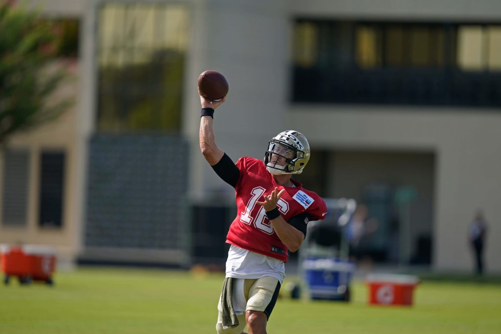 New Orleans Saints quarterback Ian Book in red practice jersey throwing pass during NFL training Wallpaper