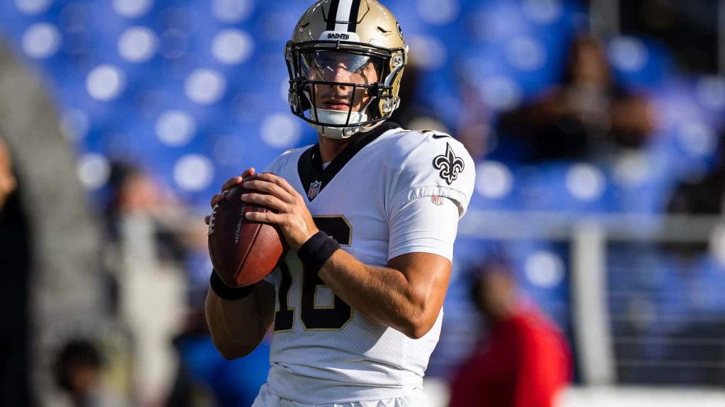 New Orleans Saints quarterback Ian Book in white uniform holding football in stadium wallpaper