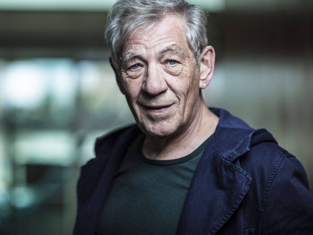 Ian McKellen portrait wallpaper with thoughtful expression and striking blue eyes in dark jacket