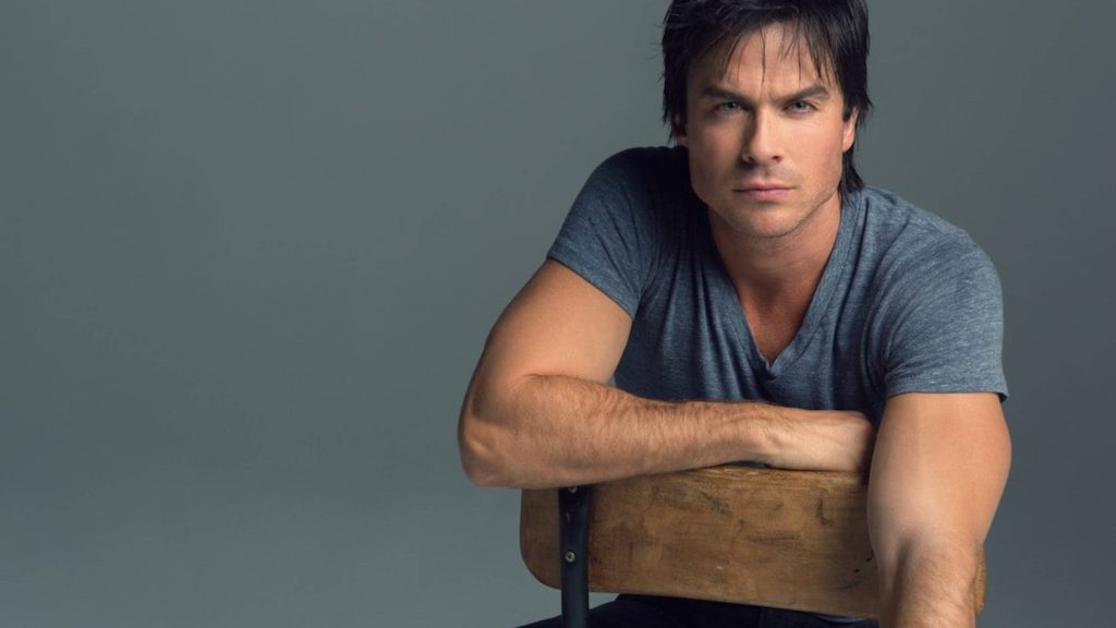 Ian Somerhalder intense studio portrait casual grey t-shirt leaning on wooden chair gray background Wallpaper
