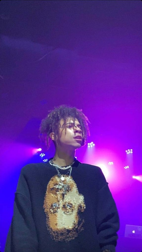 Iann Dior live performance wallpaper purple lighting black sweater layered necklaces music fan background