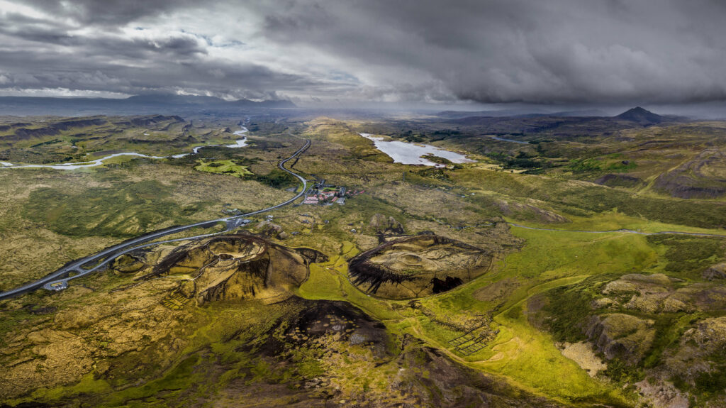 Aerial view of Iceland landscape with deep craters winding fjords lush greenery and storm clouds Wallpaper