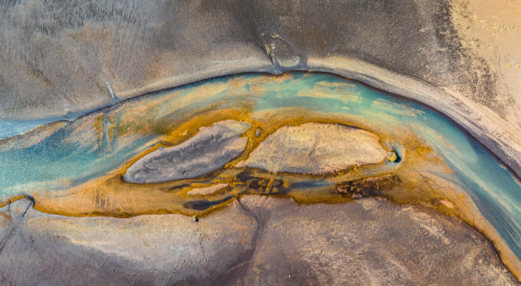 Aerial view of Iceland winding turquoise river golden sandy banks and textured earthy landforms Wallpaper