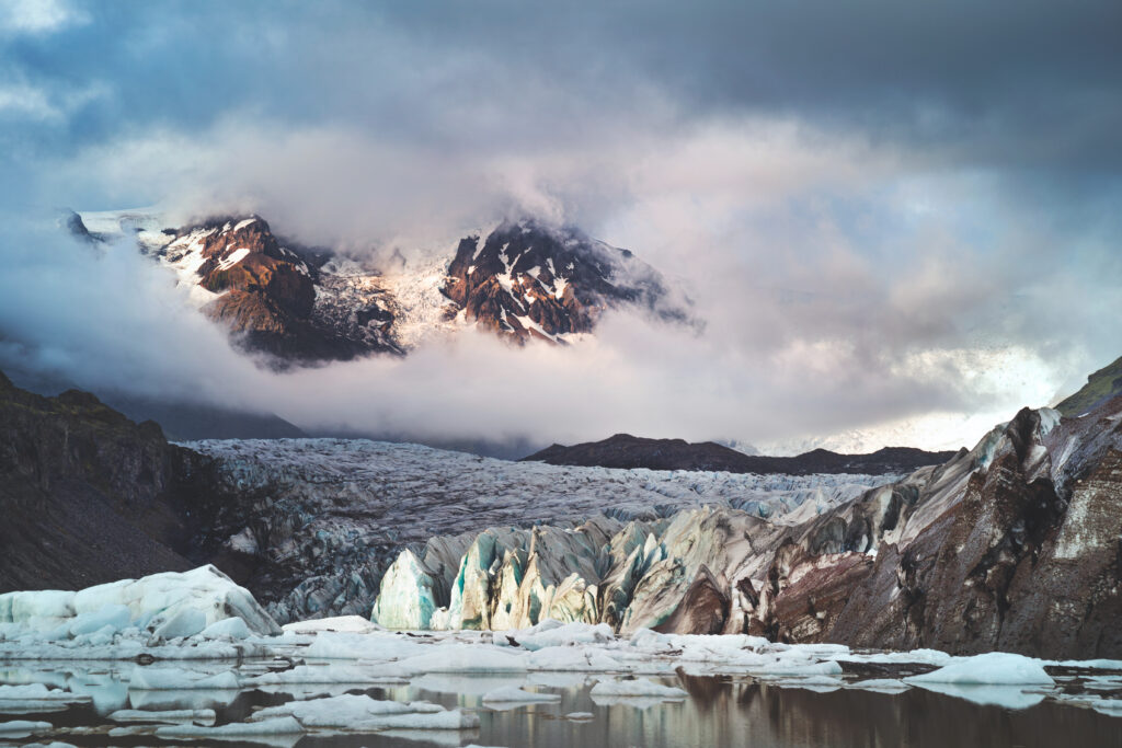 Dramatic Icelandic landscape with glaciers rugged mountains swirling clouds and icy blue tones Wallpaper