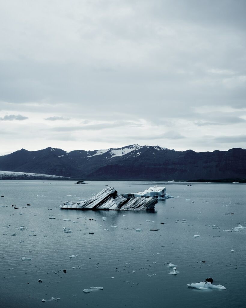 Serene Icelandic lake with icebergs and rugged mountains under dramatic overcast sky wallpaper