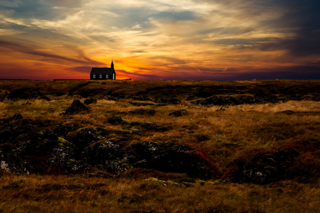 Solitary Iceland church at sunset with golden grasses and rugged terrain wallpaper background
