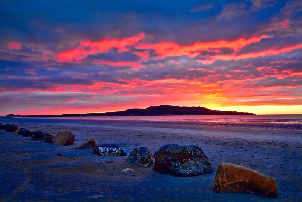 Icelandic beach with rugged rocks sandy shore dawn sky vibrant pink orange purple hues wallpaper