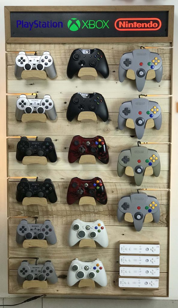 Wall-mounted display of iconic Sony PlayStation Xbox Nintendo retro and modern video game controllers Wallpaper